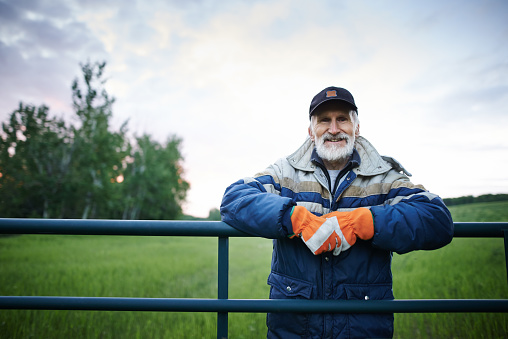 Portrait of a mature man standing at the fence of a farm