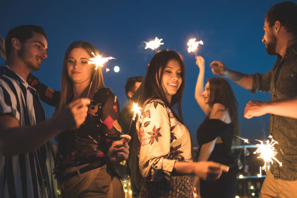 istock Friends enjoying rooftop party with sparklers 1067130614