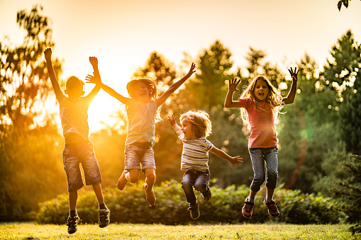 Beauty children enjoying jumping in nature at sunset