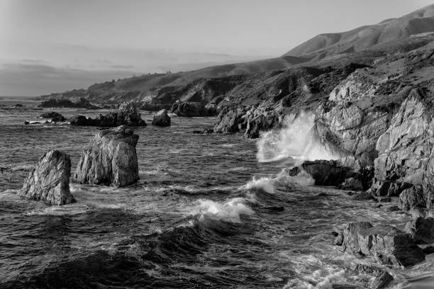 Crashing waves of water on the granite coastline of Garrapata State Park in California's Central Coast in black and white.