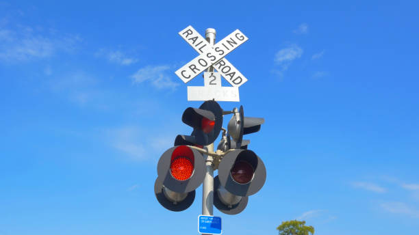 railroad crossing with active guards and lights flashing - railroad crossing railway signal gate nobody imagens e fotografias de stock