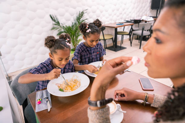 istock Dark-haired mother feeling thoughtful while her children eating lunch 1067137074