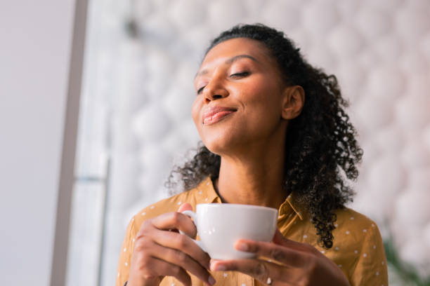 istock Curly dark-haired appealing woman feeling joyful while drinking coffee 1067143554