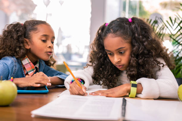 istock Curly schoolgirl wearing yellow smart watch doing her homework 1067143610