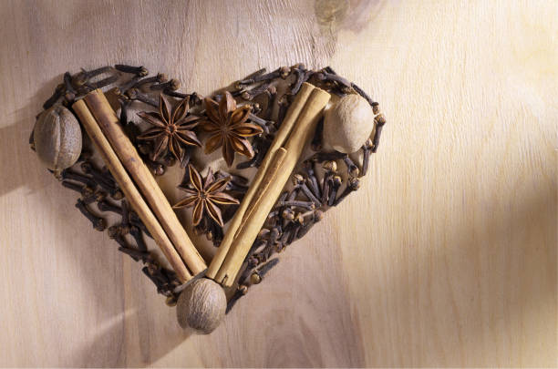 Various winter spices on a wooden background shaped as a heart, top view with copy space