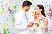 adult gentle couple with drawing equipment against painted wall