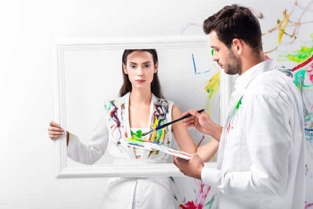 istock adult woman standing with white frame while man holding drawing equipment 1067155644