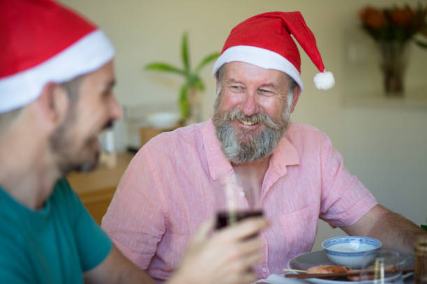 father and son talking over a glass of wine at dining table at christmas - eating child cracker asia imagens e fotografias de stock