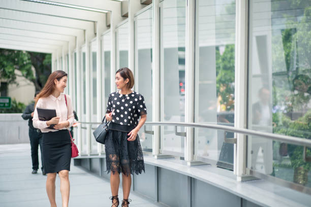 istock Two Asian women walking to work, talking as they cross a bridge 1067170512