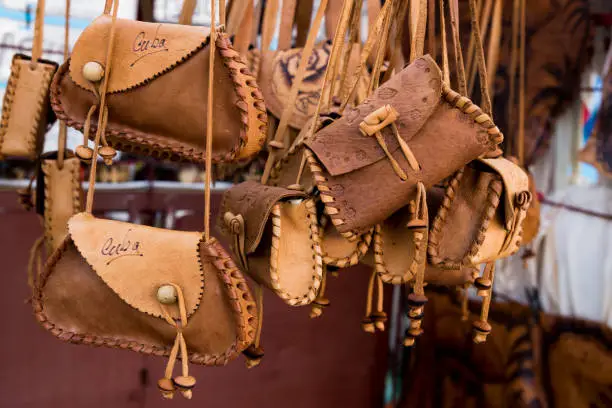 Hand tooled leather purses hanging on rack at market in Cienfuegos - Cuba