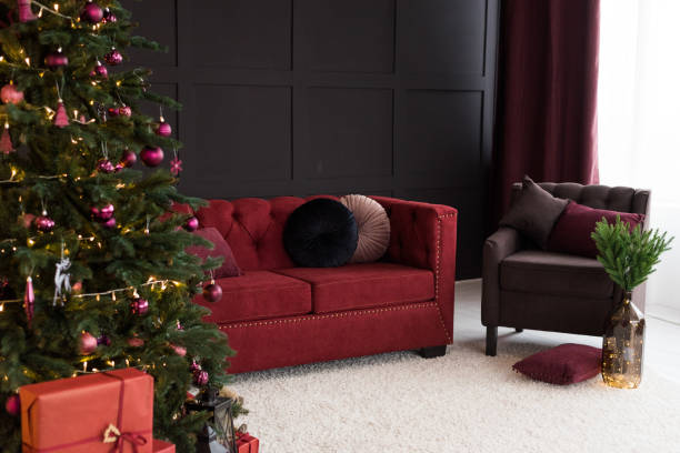 istock Thevelor sofa in the dark loft room has a bright light from the eternal light and an artificial fireplace. Inner attic with concrete walls and a decorated Christmas tree with gift boxes 1067174416