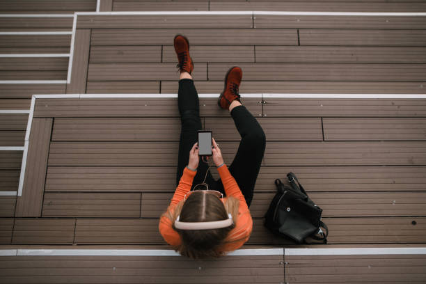 istock Young woman with smartphone sitting on staircase 1067178512