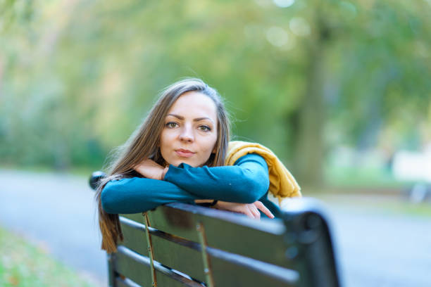istock Smiling beautiful woman sitting on bench in park 1067182070