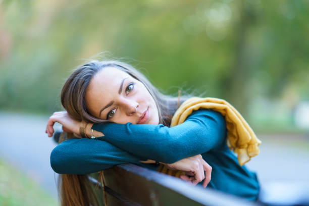 istock Smiling beautiful woman sitting on bench in park 1067182132