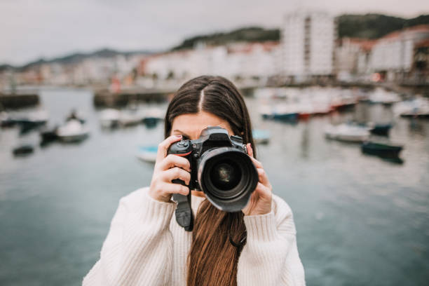 istock Young woman taking a picture with a modern DSLR camera 1067183896