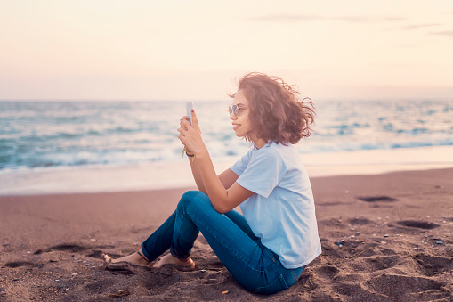 woman taking pictures on the beach with phone