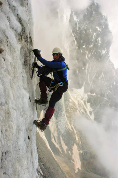 istock Climber with an ice ax climbs on a vertical ice wall 1067186992