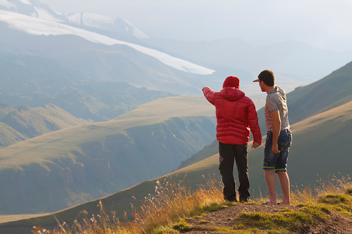 Guide pointing the way to the mountain. View from the height of the valley. Caucasus, Mount Elbrus region.