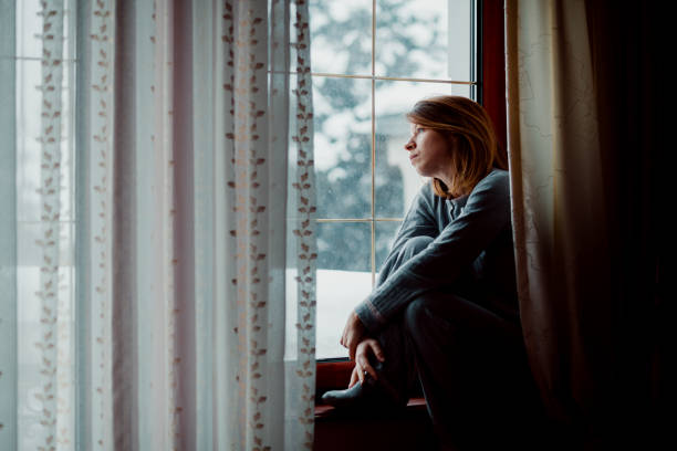 istock Sad woman sitting by the window looking outside 1067193774