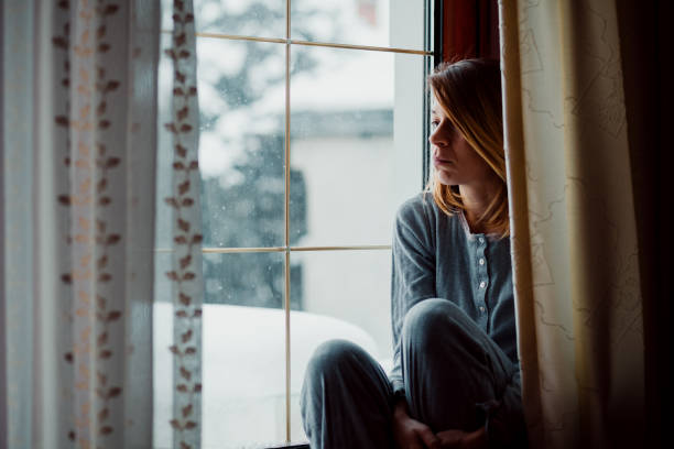 istock Sad woman sitting by the window looking outside 1067193778