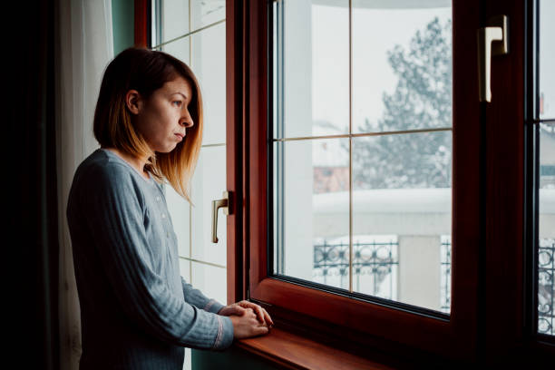 istock Sad woman sitting by the window looking outside 1067193782