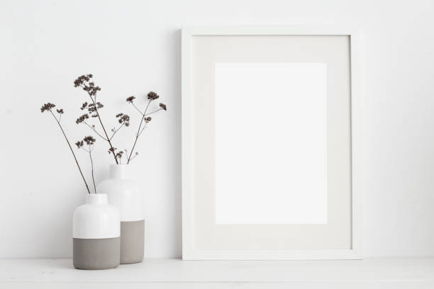 White frame and dry twigs in vase on book shelf or desk. White colors. Mock up white frame and dry twigs in vase on book shelf or desk. White colors. bookshelf photos stock pictures, royalty-free photos & images