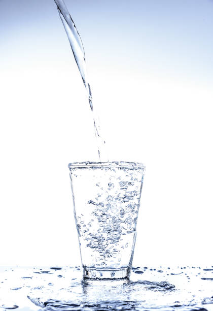 istock Pouring water and splashing in the glass with reflection on mirror. 1067198824