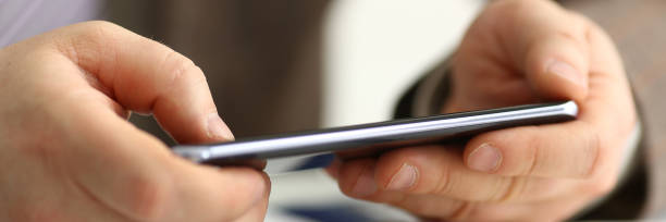 istock Male arm in suit hold phone and silver pen 1067203606