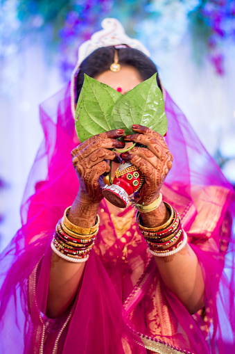 Beautiful bride performing Shubhodristi which is a Bengali culture wedding ritual done by the Bride in which she hides her face in front of the Groom.