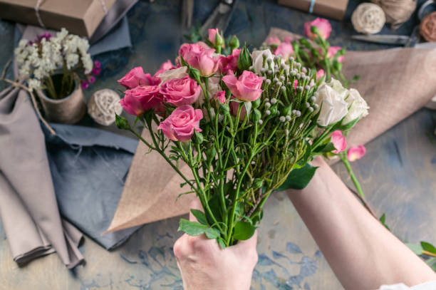istock Female hands making wedding bouquet on a dark table. Small business concept. Work process of florist. 1067243462