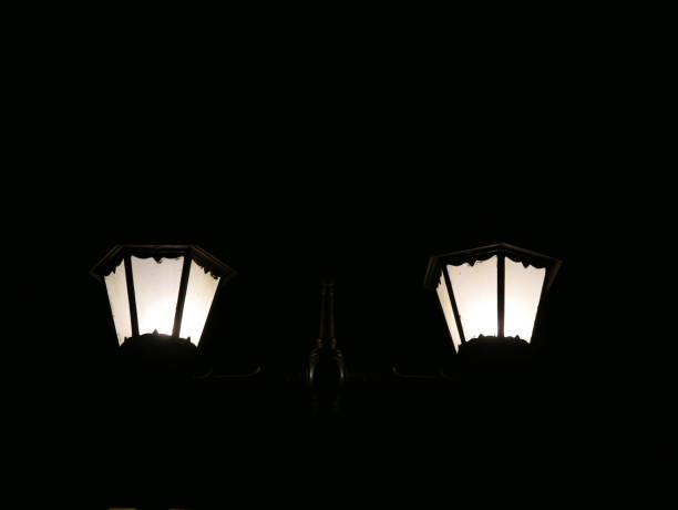 Two orange streetlights emitting a bright glow through thick fog during a dark night