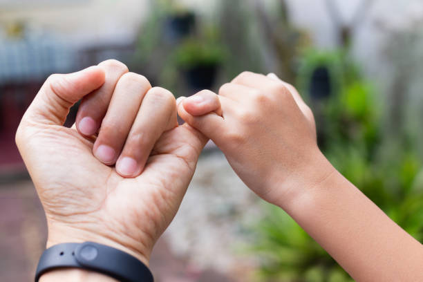 istock Father and son hands hooking each other on little finger making promise together 1067260008