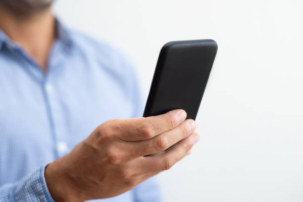 istock Closeup of man holding and browsing on smartphone 1067262154