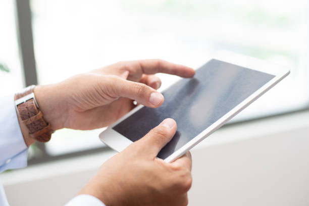 istock Close-up of busy man holding tablet and working with online data 1067263542