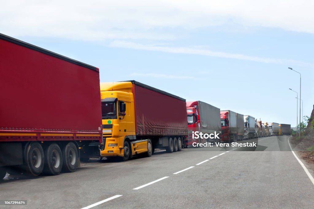 Queue of trucks passing the international border, red and different colors trucks in traffic jam on the road Truck Stock Photo