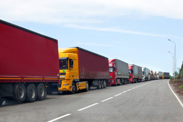 kolejka ciężarówek przejeżdżających przez granicę międzynarodową, czerwone i różne kolory ciężarówek w korku na drodze - personal land vehicle zdjęcia i obrazy z banku zdjęć