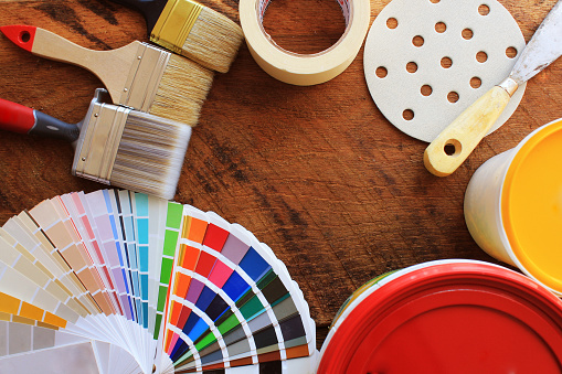 various painting tools, accessories and color samples for home renovation on wooden background .