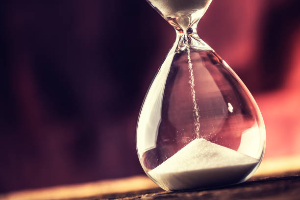 istock Modern hourglass in running time on wooden table. 1067294792
