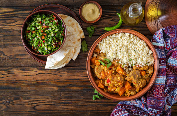 tradiční tajine pokrmy, kuskus a čerstvý salát na rustikálním dřevěném stole. tagine jehněčí maso a dýně. pohled shora. ploché lavice - domorodé obyvatelstvo etnikum - stock snímky, obrázky a fotky