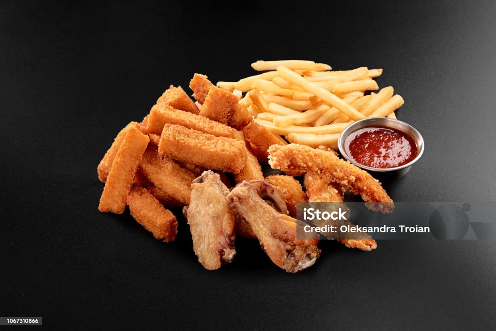 Fresh beer snacks chicken wings french fries cheese sticks assortment on black Fresh beer snacks chicken wings french fries cheese sticks assortment on black background Beer - Alcohol Stock Photo