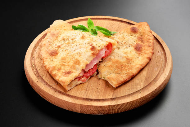 바 질으로 피자 calzone 나뭇잎 가까이 나무 라운드 보드에 토마토 치즈와 햄 절연 cutted - pizza pastry crust stuffed cheese 뉴스 사진 이미지