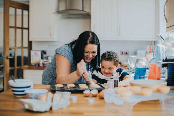 istock Mother helping son to put frosting onto cupcakes 1067314674