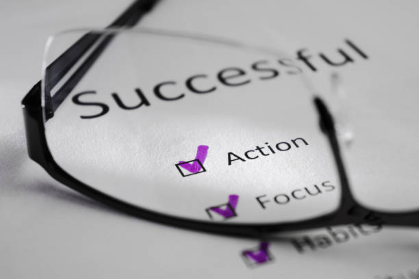 ACTION inscription on a white sheet. This is a motivational checklist with points for success. Opposite the lines there are check marks in black squares. The picture was taken through the lens of glasses and highlighted by a beam of light.