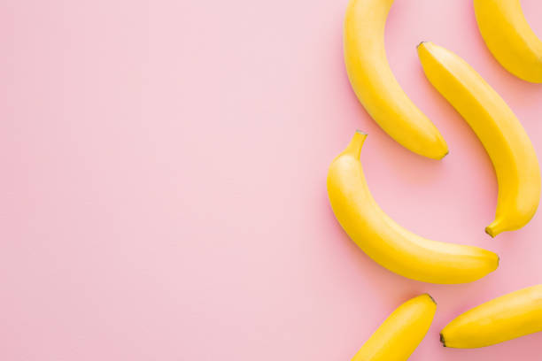 Beautiful, fresh, yellow bananas on pastel pink background. Mockup for different ideas. Empty place for text, quote or logo. Top view.