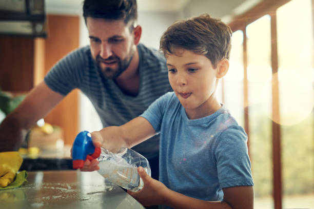 Take that germs! Shot of a father and son cleaning the kitchen counter together at home tidy room stock pictures, royalty-free photos & images