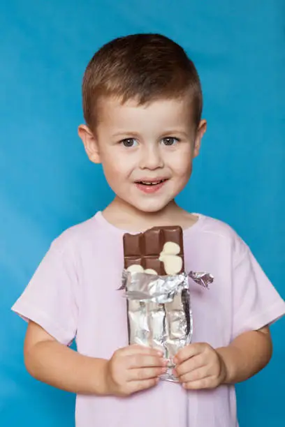 Cute Little Boy Eating Chocolate Bar. Very cute kid with chocolate, isolated. Happy boy with chocolate bar