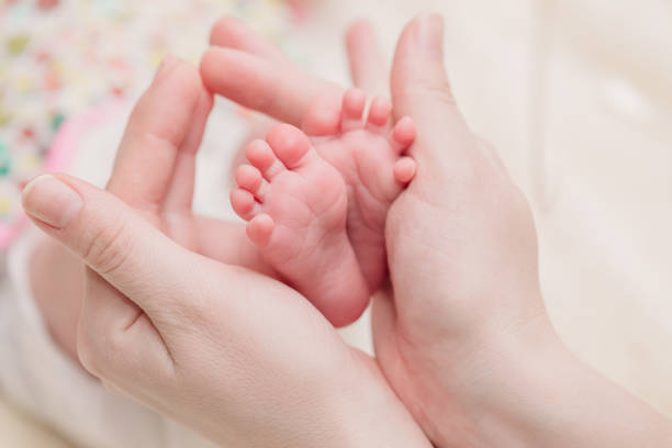 istock Mom holds small baby legs in hands 1067334978