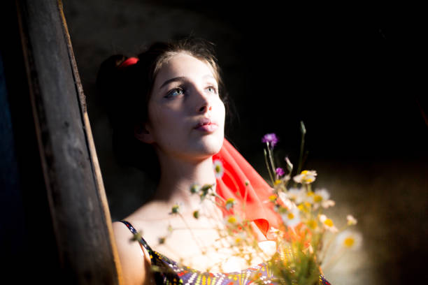 A young woman brings a Iris flower closer to her.
