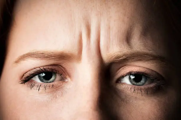 Close-up of the face of a lovely young woman frowning and looking worried.