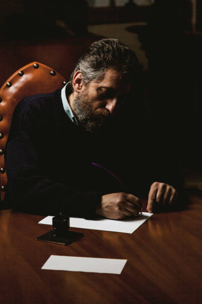 istock writer with beard writes on white sheet with goose feather 1067337772